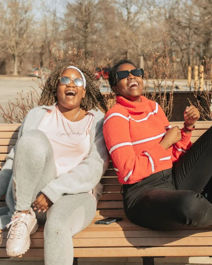 Two friends laughing on a bench
