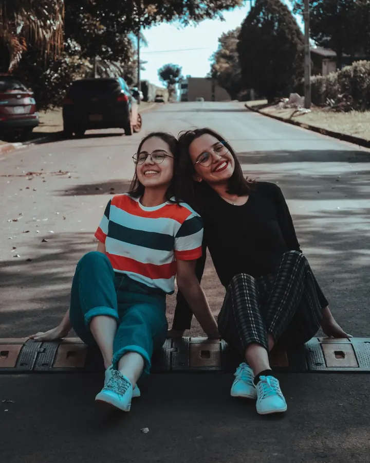 Two friends sitting together on a quiet street